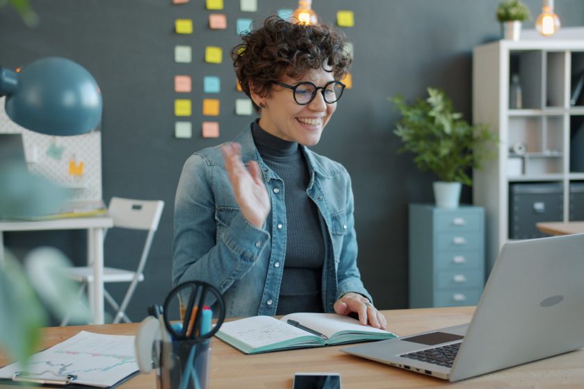 Femme souriante en visioconférence dans son bureau moderne