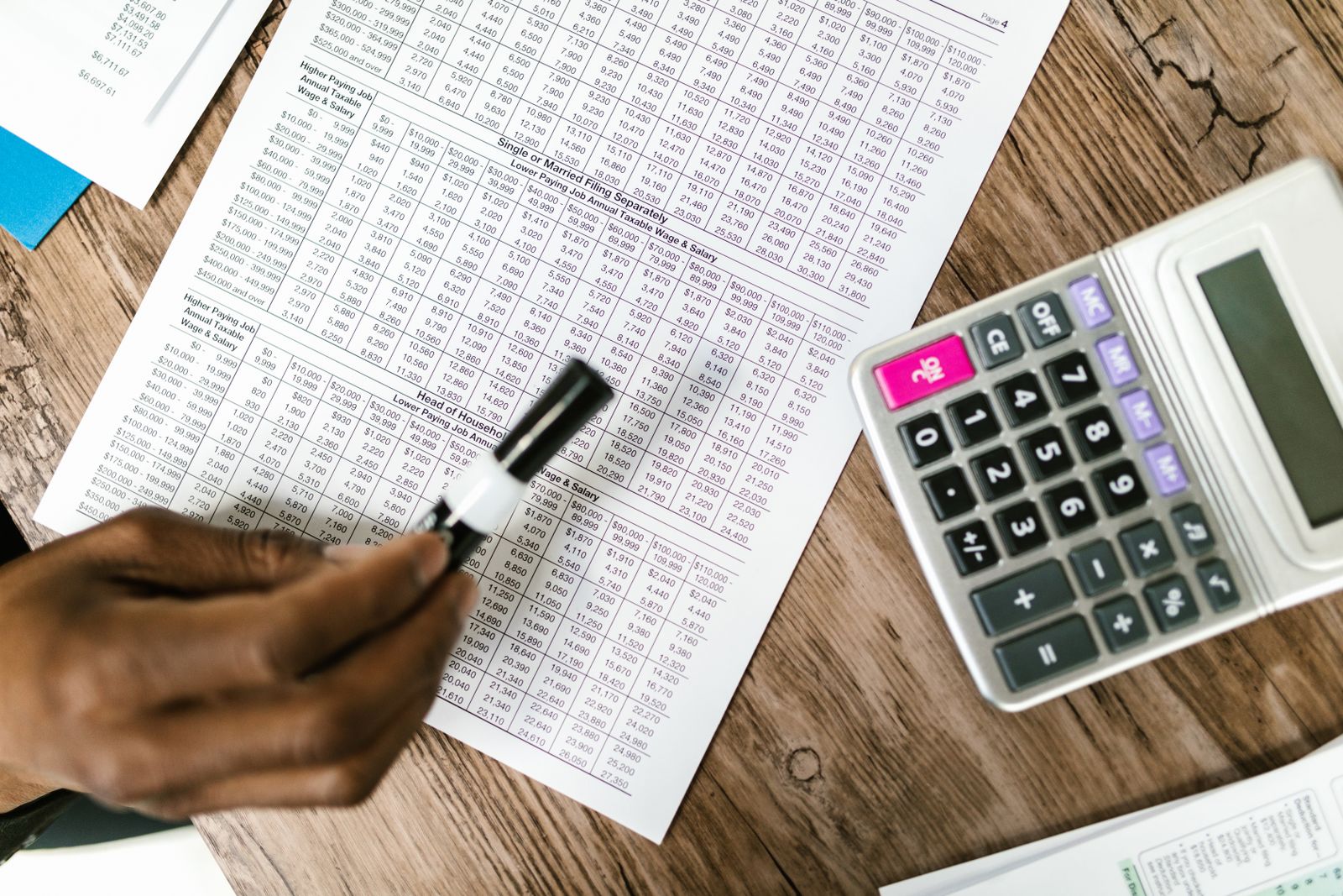 Calculatrice posée sur des relevés, sur un bureau en bois