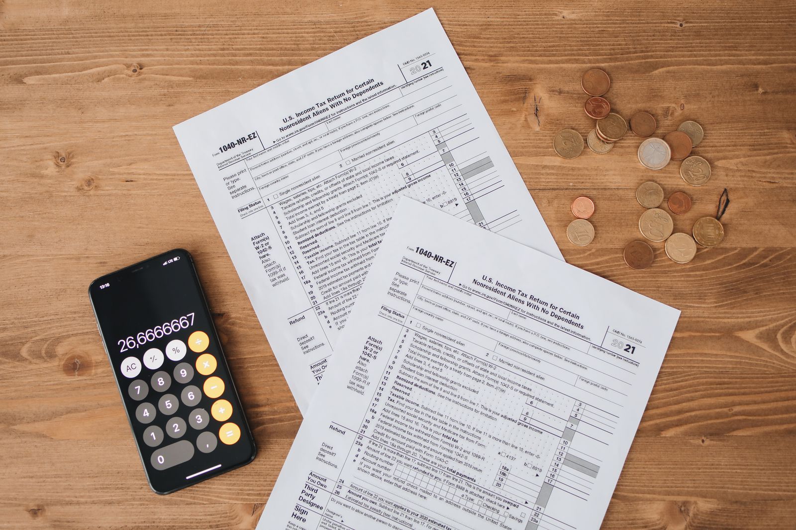 Formulaires fiscaux, calculatrice et pièces de monnaie sur une table en bois