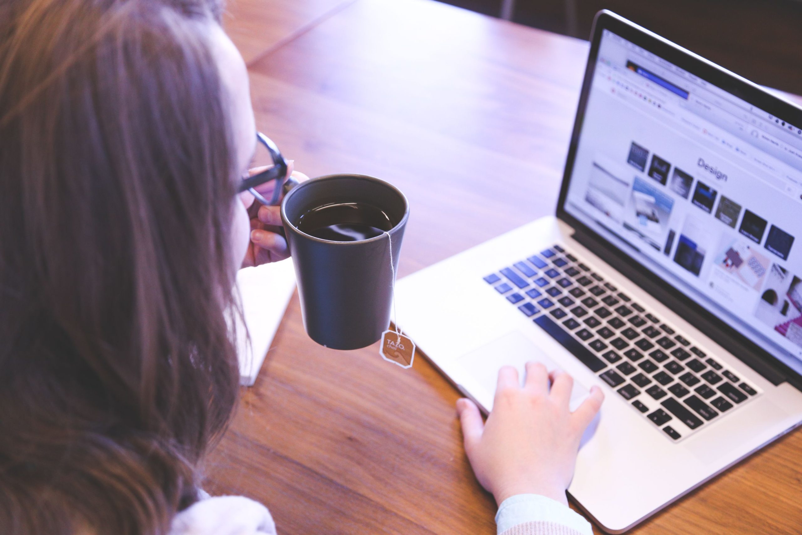 Femme prenant un cafe en travaillant sur laptop a domicile