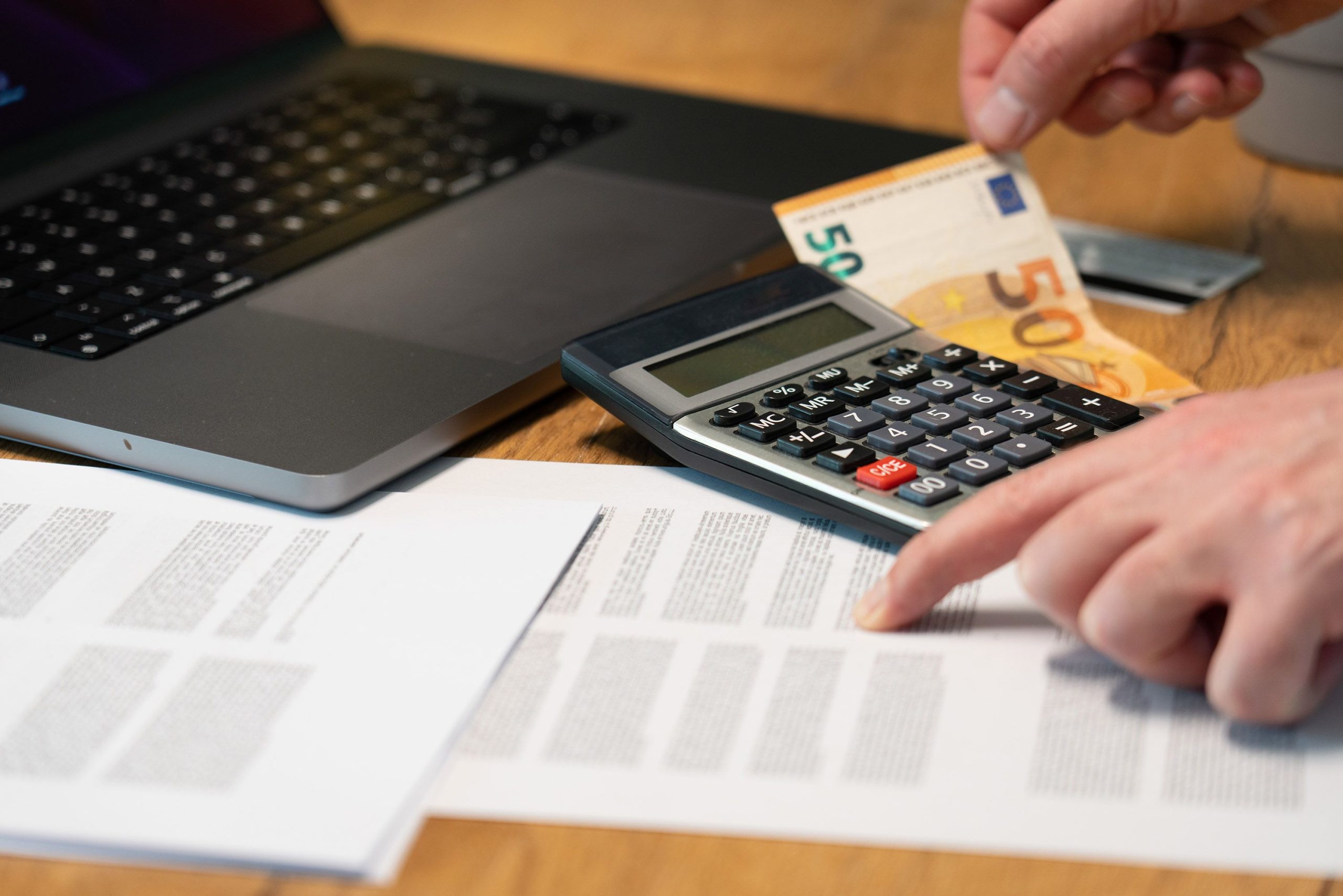 Mains utilisant une calculatrice près de billets en euros