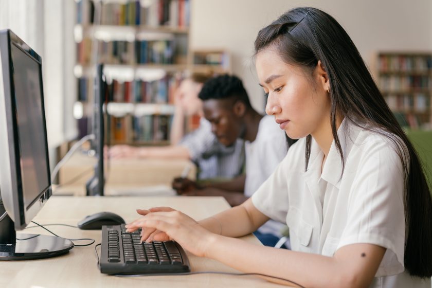 Étudiants utilisant ordinateurs en bibliothèque pour recherche académique