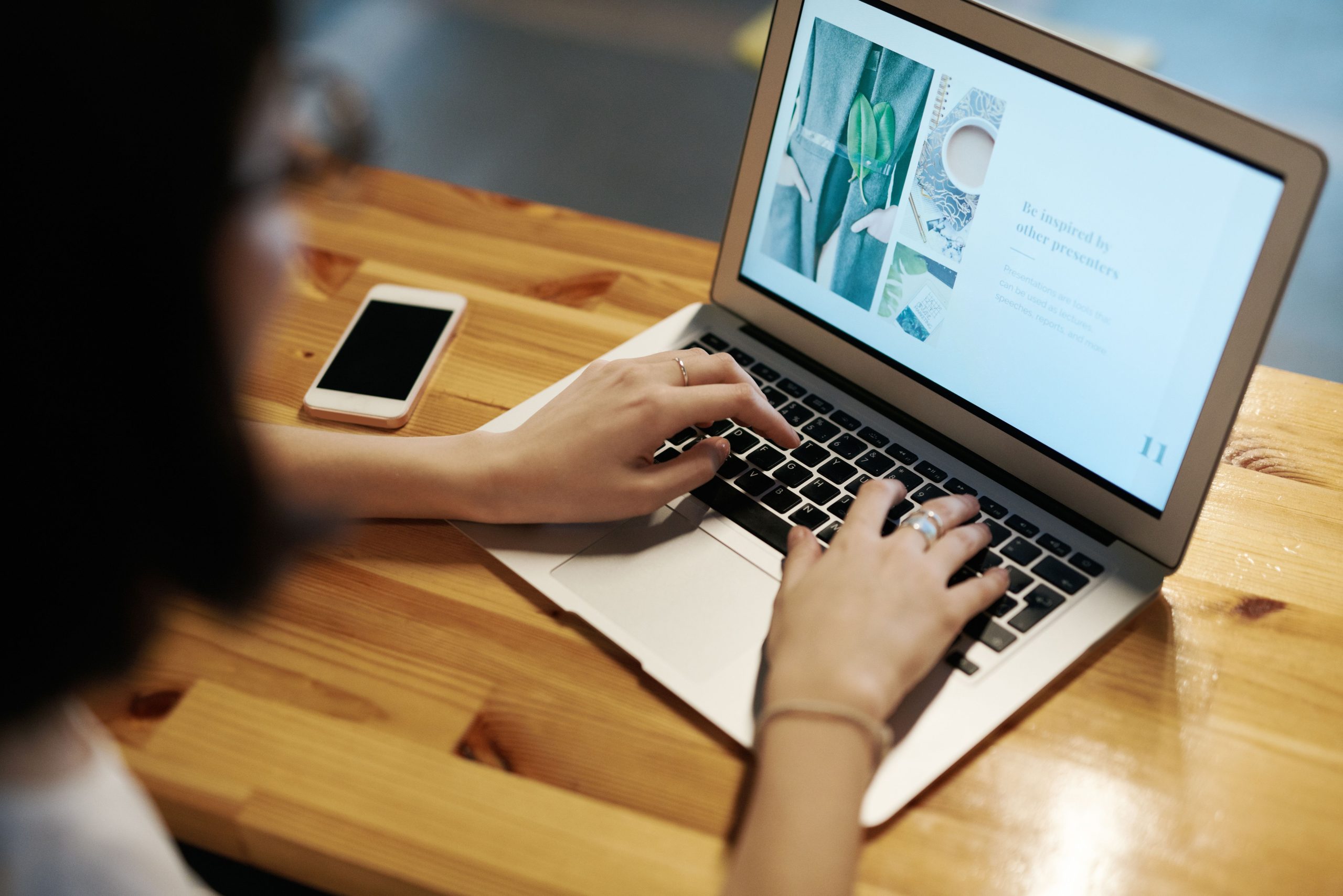 Personne tapant sur laptop à table en bois avec smartphone
